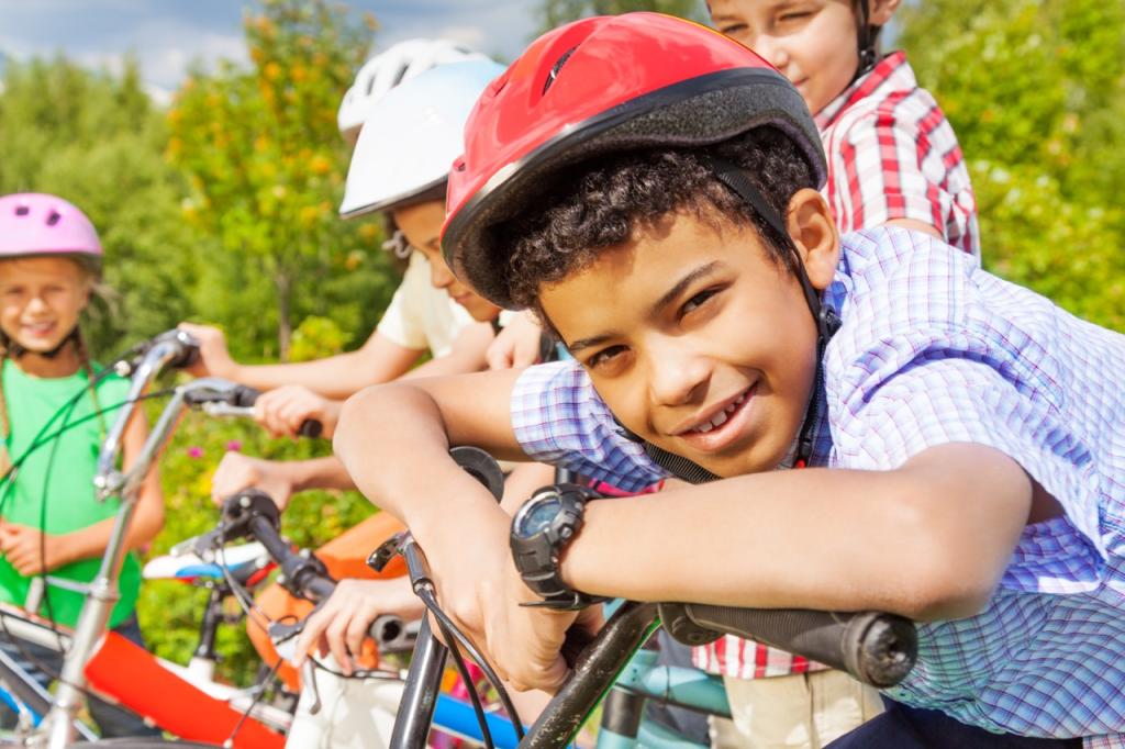Smiling boy in helmet holds handle-bar of bike